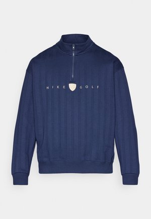 Marineblauwe Nike Golf pullover, met een halflange rits, ribbelstructuur en een logo op de borst. De materialen lijken zacht en ademend.