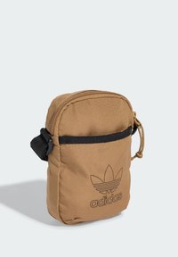 Borsa a tracolla in tessuto marrone con zip superiore, tracolla nera e logo Adidas impresso sul davanti. Forma compatta e rettangolare.