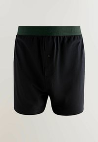 Melni kokvilnas bokseri ar zaļu elastīgu jostu, priekšā ar pogu un gludu tekstūru. Vienkāršs, funkcionāls dizains.