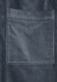 Dark gray towel made of soft, textured fabric with a square pocket and embroidered "VOSSEN" logo. Edges are neatly finished.