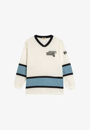 Langærmet skjorte i creme med sorte og lyseblå vandrette striber. V-hals designet har et abstrakt grafisk motiv på venstre bryst.