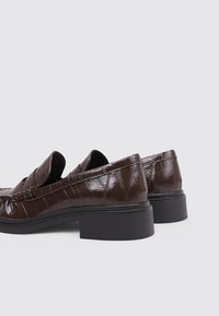 Brown leather loafers with a glossy finish, featuring a textured crocodile pattern and a low, chunky heel.