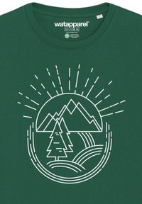 T-shirt en coton vert avec un graphique blanc représentant des montagnes, un arbre et des vagues, entourés de rayons de soleil.