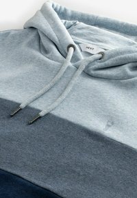 Sweater met capuchon met een driekleurig ontwerp in lichtblauw, donkerblauw en grijs. Gemaakt van zachte stof met getextureerde koordjes en zilveren accenten.