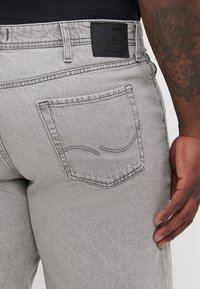 Grijze denim jeans met een rechte pasvorm, voorzien van een achterzak met subtiele stiksels en een gestructureerd zwart lederen label boven de tailleband.