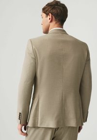 Beige Anzugjacke mit Nadelstreifen, mit eingeschnittenen Revers, einzelner Rückenbelüftung und Viertelknopfmanschetten. Glatte Stofftextur, taillierte Passform.