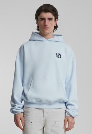 Lichtblauwe hoodie van zacht materiaal, met een voorzak en ribbelrand. Zwart geborduurd logo op de linkerborst.