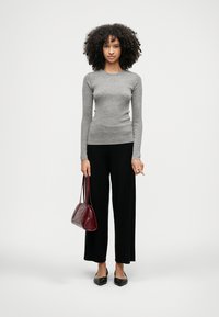 Šedé rebrované tričko s dlhým rukávom v kombinácii s čiernymi nohavicami s širokými nohavicami, čiernymi balerínkami a malou bordovou kabelkou. Jednoduchý a čistý dizajn.