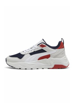 Biało-granatowo-czerwony sneaker Puma z grubą podeszwą, cholewką z siateczki i skóry oraz logo na pięcie, widoczny z boku.
