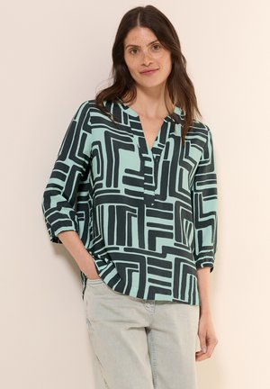 Blouse à manches longues en V mint clair avec un motif géométrique noir. Dotée de manches retroussées et d'une coupe décontractée.
