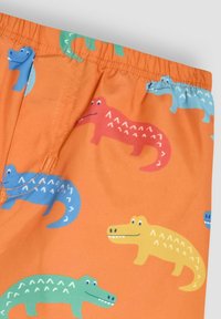 Shorts mit orangefarbenem Grund, versehen mit bunten Krokodilmustern in Blau, Grün, Rot und Gelb. Elastischer Bund, glatte Textur.