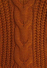 Stickad tyg i varm orange med intrikata kabelmönster och en texturerad, tjock design med växlande öppna och stängda stygn.