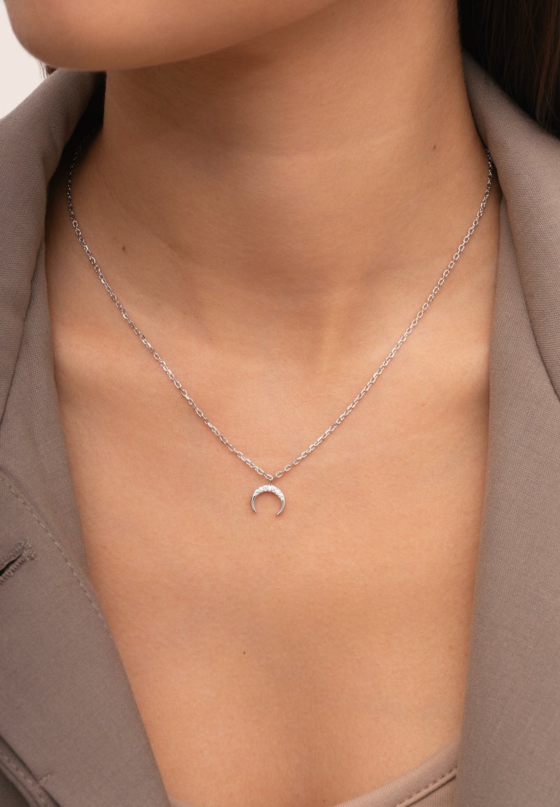 Collana in argento con una delicata catena e un pendente a forma di mezzaluna, caratterizzato da una finitura liscia e un design minimalista.