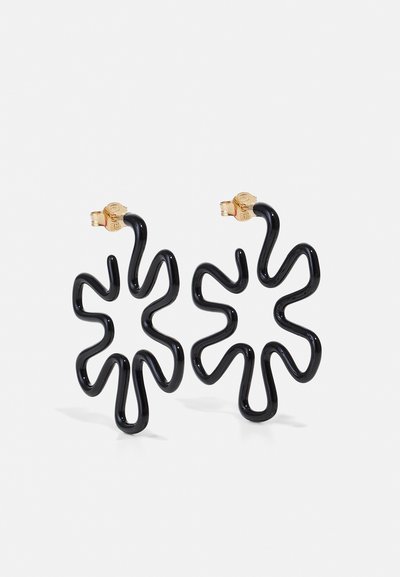Pendientes de plástico negro con forma floral ondulada. Herrajes en tono dorado utilizados para el cierre. Textura suave y diseño ligero.