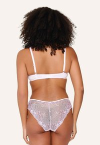 Weißer Spitzen-BH mit verstellbaren Trägern und einem Rückverschluss, kombiniert mit transparenten rosa Spitzenpanties mit floralem Muster und schmalem Sitz.