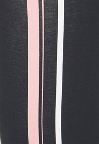 Černé legíny s třemi vertikálními pruhy v světle růžové, bílé a černé barvě. Tkanina má hladkou texturu a mírnou pružnost.