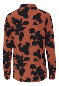 Chemise à manches longues couleur rouille avec motif de feuilles noires, tissu texturé, col à boutons et poignets boutonnés. Comprend un ourlet arrondi.