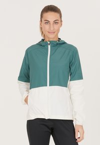 Gemêleerd jack in teal en wit, met een twee-kleurig ontwerp, volledige rits aan de voorkant en gouden hardware-accenten. Lichtgewicht stof met een gladde textuur.