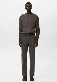 Suéter marrón de punto acanalado combinado con pantalones ajustados verde oliva y zapatos marrones; presenta un cuello redondo y un diseño de ajuste ceñido.