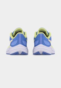 Ζεύγος αθλητικών παπουτσιών σε μπλε και λαχανί απόχρωση, που φαίνονται από πίσω, με επενδυμένες φτέρνες και λευκές ενδιάμεσες σόλες σε λευκό φόντο.