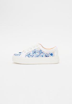 Valged tossud esitlevad siniseid lillemotiive tikandina varvaste ja külgedel, sileda kangast pealmise osa ning tekstuurse kummist tallaga.