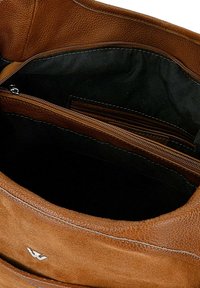 Bruine leren handtas met een gestructureerde buitenkant en een gladde voering; heeft een ritsvak aan de binnenkant en een subtiele logo-accent.