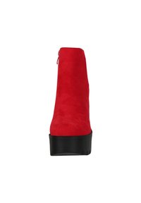 Botín de ante rojo hasta el tobillo con una plataforma alta y tacón cuadrado. Presenta un zipper lateral y suela de goma negra lisa.