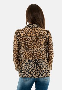 Camicetta con stampa leopardata in tonalità di marrone e nero, con colletto, maniche lunghe e vestibilità comoda. Tessuto testurizzato con finitura morbida.