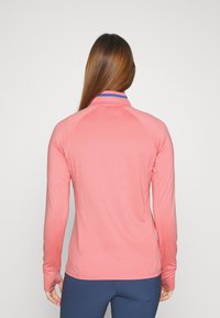 Dlouhý rukáv sportovní tričko v gradientní korálové barvě, s límcem v modrých akcentách, hladkou texturou a přiléhavým střihem pro pohodlí.