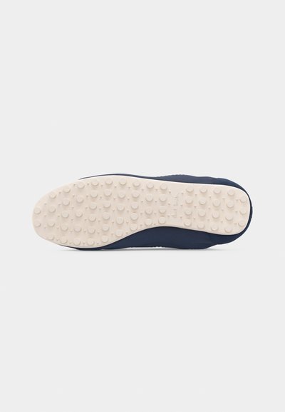 Σόλα ναυτικού παπουτσιού με εξωτερική σόλα από λευκό-κρεμ καουτσούκ, που διαθέτει ανάγλυφες κυκλικές τάπες και την ένδειξη "Paul Smith" κοντά στην καμάρα.