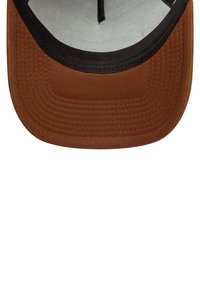 Gorra de tela marrón con visera negra, costuras texturizadas y forro interior de un color claro. Diseño accesible para mayor comodidad.