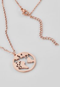 Collana in oro rosa con pendente circolare con design a mappa del mondo ritagliato. La catena è dotata di un gancio a moschettone e di link intricati.