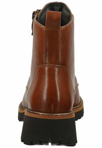 Brown leather ankle boot with a textured finish, chunky black sole, rear zipper, and subtle metallic accent on the sole edge.
