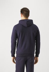 Marineblaues Sweatshirt mit Kapuze, im lässigen Schnitt, mit gerippten Bündchen und Saum, aus weichem, strukturiertem Stoff, von hinten betrachtet.