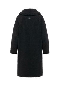 Svart, lång, oversized kappa gjord av texturerat tyg. Har en krage och en liten logotyp på baksidan. Inga synliga stängningar.