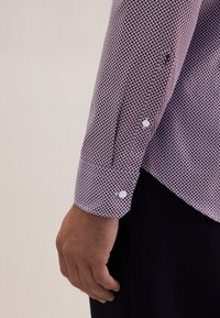 Langarmige gebloemde shirt in bordeauxrood en lichtblauw met een gestructureerde stof, voorzien van witte knoopdetails op de manchetten.