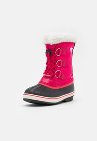 Botín de invierno rosa con una sección inferior de goma negra, forro de forro polar en la parte superior y acentos de cordones metálicos. Cuenta con una suela texturizada para mayor agarre.