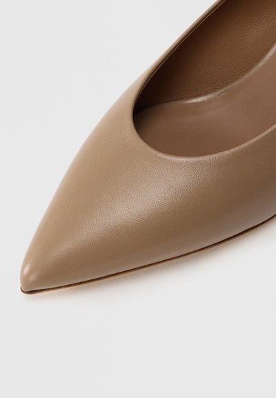 Μπεζ δερμάτινο παπούτσι με μυτερή μύτη, ομαλή υφή και σχεδιασμό με ανοίγματα στα πλάγια, που αποκαλύπτει ένα απαλό  εσωτερικό φινίρισμα.