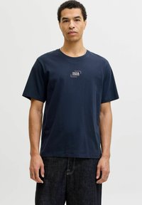 Camiseta de algodón azul marino con cuello redondo y mangas cortas, que presenta un pequeño logo bordado en el pecho y un corte recto.