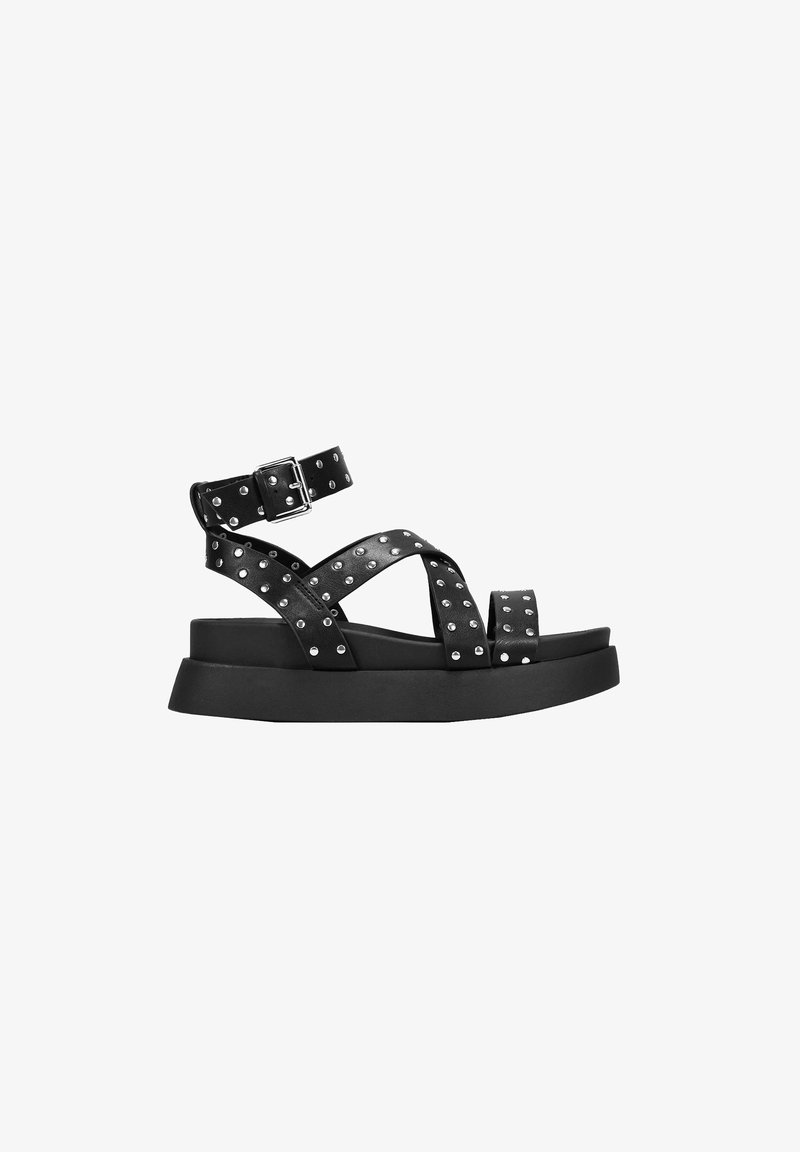 Black platform sandals with an adjustable ankle strap, featuring cross straps adorned with silver studs and a textured sole.