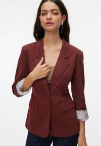 Blazer bordeaux avec revers crantés, deux poches avant et poignets rayés retroussés. Tissu lisse avec une coupe structurée.