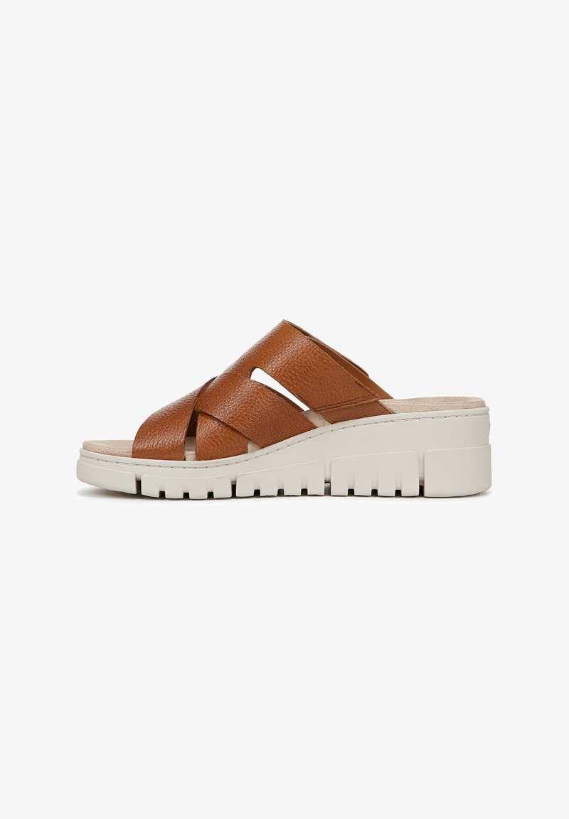 Bruine leren slip-on sandalen met een gekruist bandontwerp, gestructureerde bovenkant en een witte, grove zool met een gegroefd patroon.
