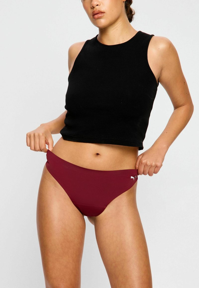 Bas de bikini bordeaux au design lisse et sans coutures. Assorti avec un haut sans manches noir. Présente un petit accent logo sur le côté.