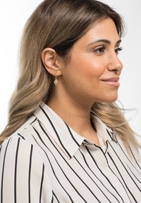 Gule hoops med en diamantformet pendel. Pendelen har en teksturert overflate som komplementerer en stripete bluse.