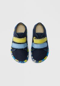 Tumesinised lõuendjalatsid siniste ja kollaste Velcro rihmadega, polsterdatud tallaga ja värvilise mustriga kummist tallaosaga. Omavad ümarat varbasõna disaini.