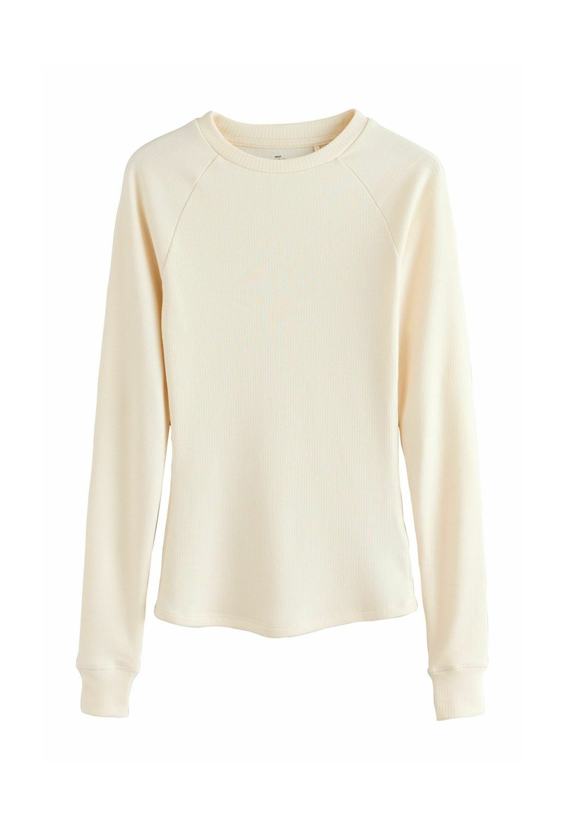 Krém színű, hosszú ujjú póló bordás anyagból. Kerek nyakkivágással és rakott ujjakra szabott illeszkedő mandzsettákkal rendelkezik.