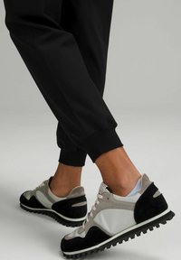 Buty sportowe z połączeniem szarej skóry i czarnego zamszu. Teksturowana podeszwa z wyraźnymi wypustkami dla lepszej przyczepności, zaprojektowane z myślą o komforcie i stylu.