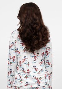 Camiseta de pijama de manga larga hecha de tela suave, con patrones coloridos de muñecos de nieve y muñequitas de nieve sobre un fondo blanco.