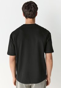 Black short-sleeve t-shirt with a round neckline and a relaxed fit, made from soft cotton fabric, minimal details, and no visible logos.