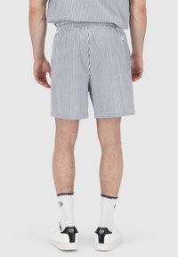 Stripete shorts med elastisk midje. Blå og hvit bomullsstoff, midt-lår lengde, paret med hvite sneakers og sokker.